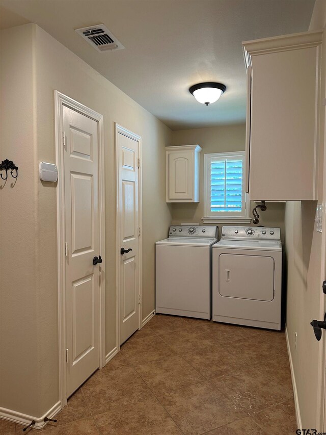 washroom with cabinet space, baseboards, visible vents, and washer and clothes dryer