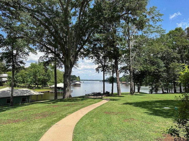view of community featuring a lawn, a water view, and a dock