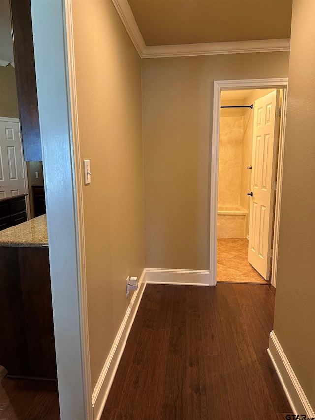 hall featuring dark wood-type flooring, ornamental molding, and baseboards