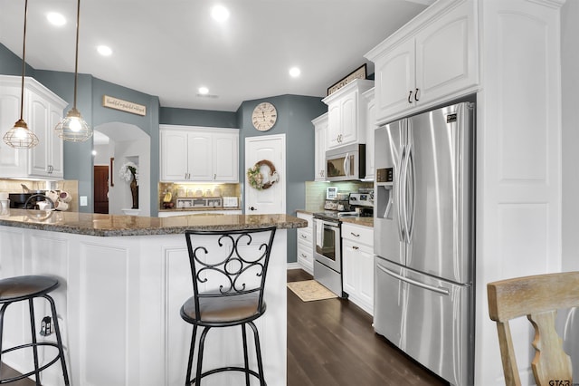 kitchen featuring dark stone counters, white cabinetry, appliances with stainless steel finishes, and decorative backsplash