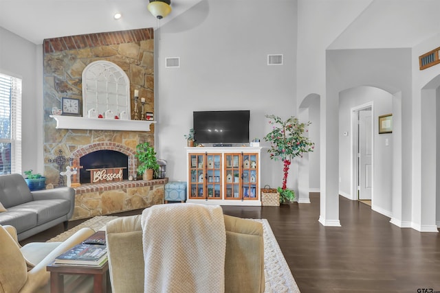 living room featuring a stone fireplace and dark wood-type flooring