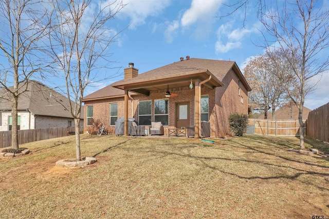 rear view of property with ceiling fan and a lawn