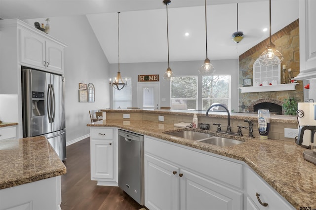 kitchen featuring appliances with stainless steel finishes, white cabinetry, sink, hanging light fixtures, and vaulted ceiling