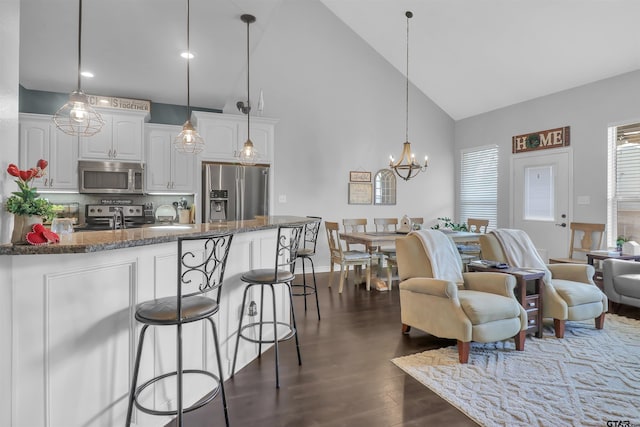 living room featuring a notable chandelier, high vaulted ceiling, dark wood-type flooring, and sink