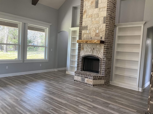 unfurnished living room featuring built in features, a fireplace, baseboards, and wood finished floors