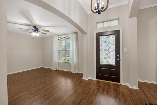 entryway with arched walkways, baseboards, ornamental molding, and dark wood-type flooring