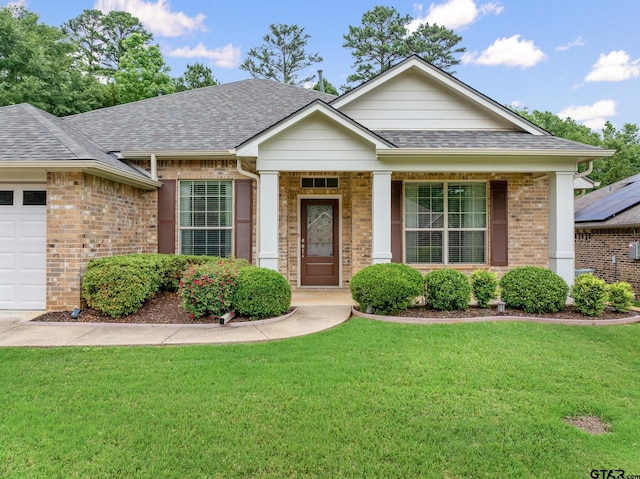 ranch-style house featuring roof with shingles, an attached garage, a front yard, and brick siding