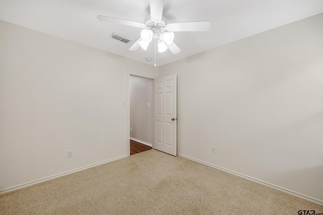 carpeted spare room featuring ceiling fan, visible vents, and baseboards
