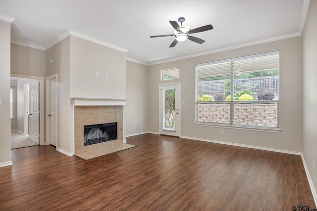 unfurnished living room featuring ceiling fan, a tiled fireplace, wood finished floors, baseboards, and ornamental molding