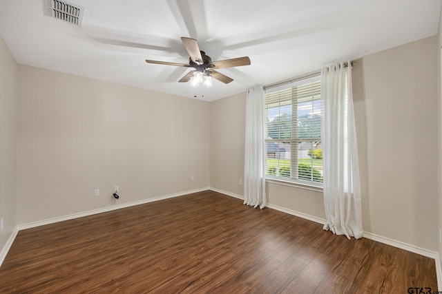 spare room featuring visible vents, a ceiling fan, baseboards, and dark wood-style floors