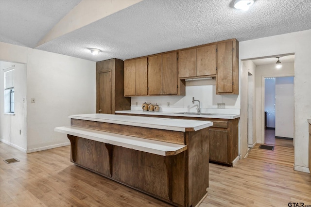 13386 Fm 858, Ben Wheeler, TX 75754 - kitchen featuring a sink, light countertops, a textured ceiling, light wood-style floors, and a kitchen island