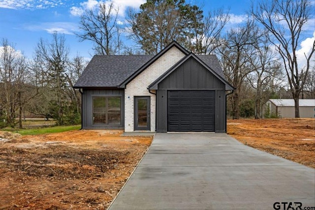 exterior space featuring board and batten siding, brick siding, a shingled roof, and an attached garage