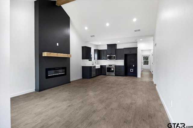 unfurnished living room featuring light wood-style flooring, recessed lighting, a fireplace, a sink, and baseboards