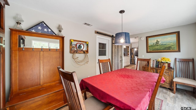 dining area featuring a barn door and light hardwood / wood-style flooring