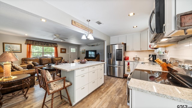 kitchen featuring white cabinetry, appliances with stainless steel finishes, hanging light fixtures, sink, and a center island