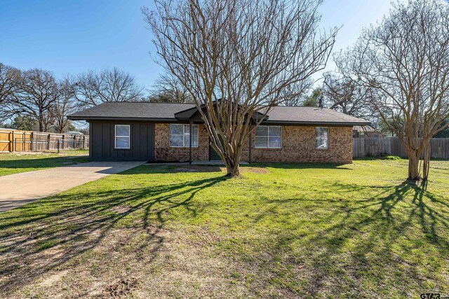 single story home with board and batten siding, a front yard, brick siding, and fence