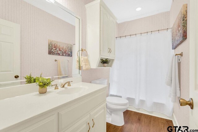 full bath with toilet, shower / tub combo with curtain, vanity, wood finished floors, and wallpapered walls