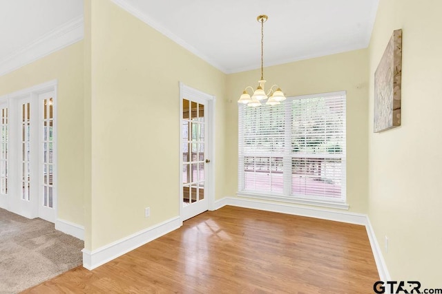unfurnished dining area with ornamental molding, baseboards, a chandelier, and wood finished floors