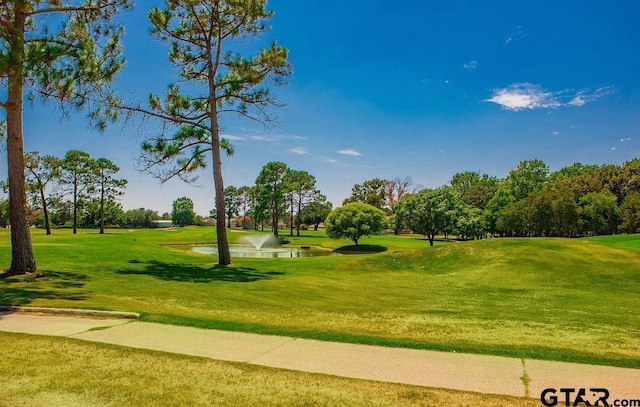 view of home's community with golf course view, a water view, and a yard