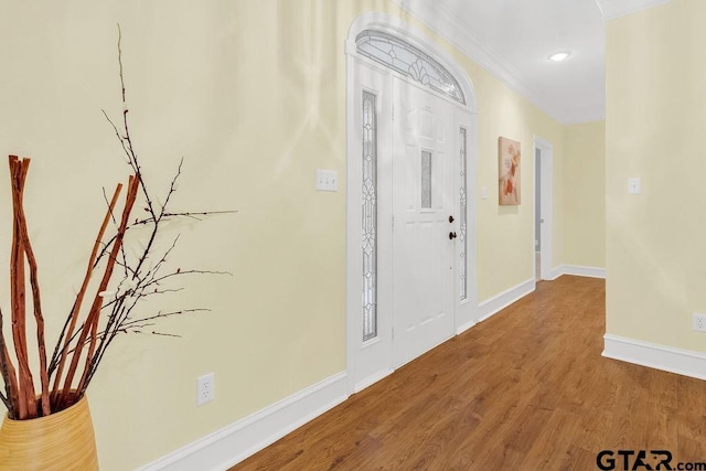 foyer with baseboards, crown molding, wood finished floors, and recessed lighting