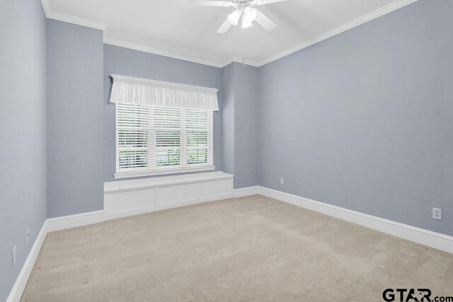 carpeted spare room featuring baseboards, ornamental molding, and a ceiling fan