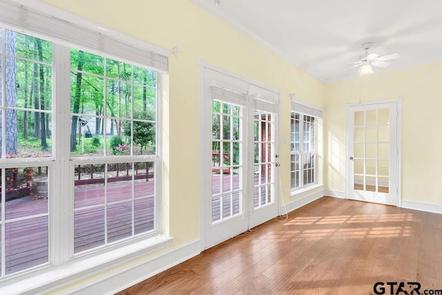 unfurnished sunroom featuring french doors, baseboards, and wood finished floors