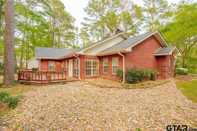 back of house with a wooden deck, brick siding, a shingled roof, and a chimney