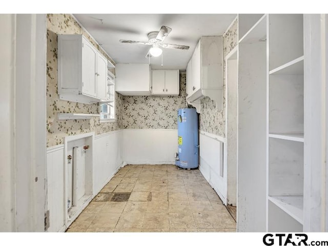 clothes washing area featuring gas water heater, a wainscoted wall, ceiling fan, and wallpapered walls