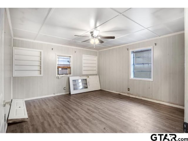 unfurnished living room featuring ceiling fan, cooling unit, wood finished floors, baseboards, and crown molding