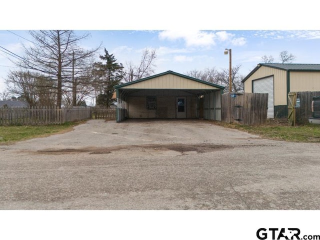 exterior space featuring a detached garage, fence, and a carport