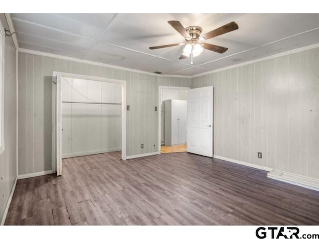 unfurnished bedroom featuring ceiling fan, wood finished floors, baseboards, a closet, and crown molding