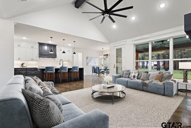 living room with beam ceiling, ceiling fan with notable chandelier, high vaulted ceiling, and sink