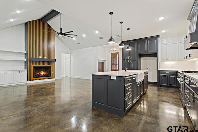 kitchen with pendant lighting, a kitchen island with sink, sink, a large fireplace, and white cabinetry