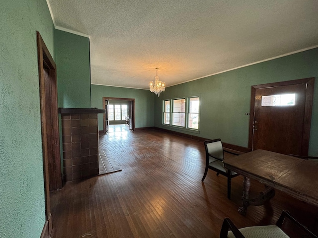 foyer with baseboards, an inviting chandelier, a textured ceiling, crown molding, and wood finished floors