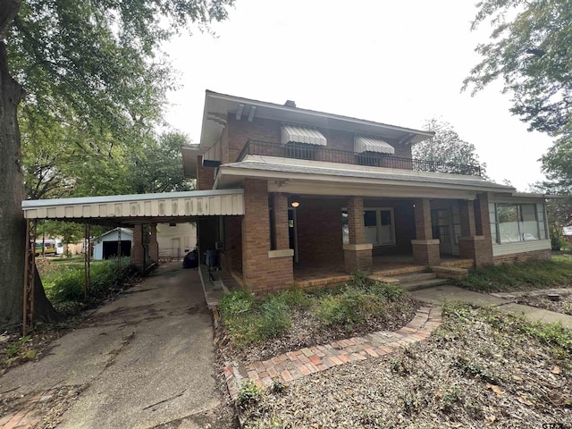 view of front facade with a carport, covered porch, driveway, and brick siding