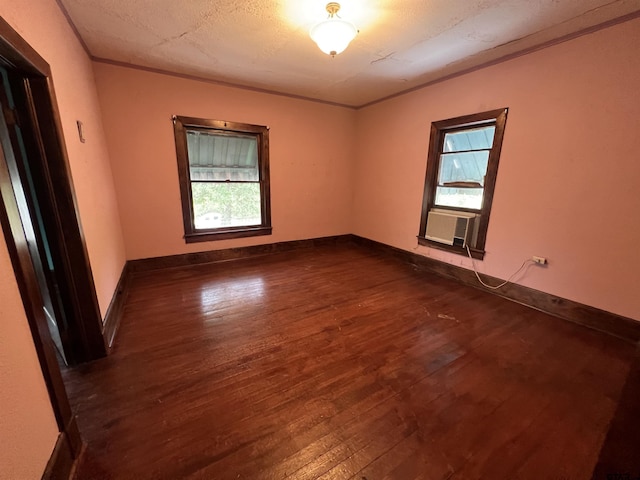 spare room featuring cooling unit, dark wood-style flooring, baseboards, and ornamental molding