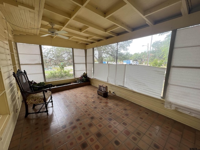 unfurnished sunroom featuring a ceiling fan and beam ceiling