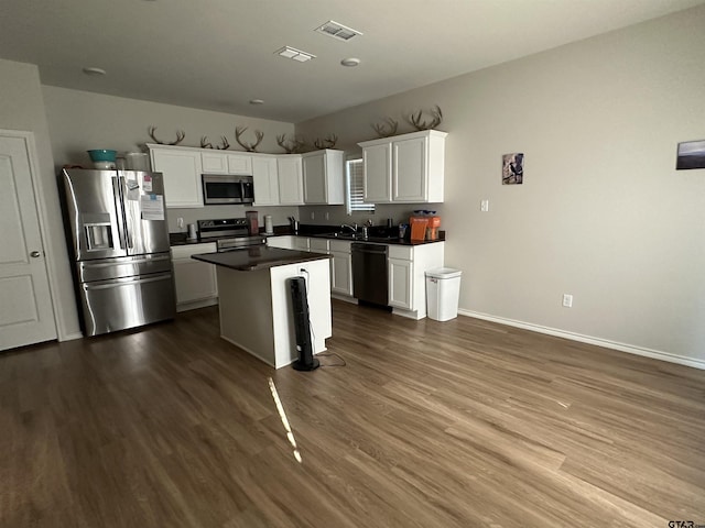 kitchen with sink, white cabinets, dark hardwood / wood-style floors, a kitchen island, and appliances with stainless steel finishes