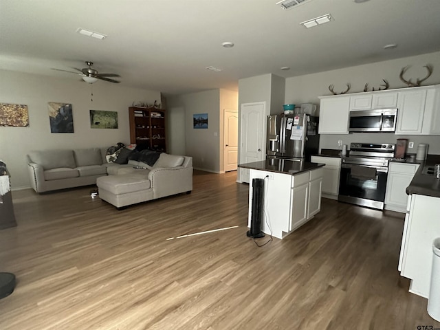 kitchen featuring ceiling fan, white cabinetry, stainless steel appliances, wood-type flooring, and a kitchen island