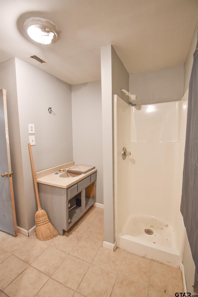 full bath with a stall shower, baseboards, and tile patterned floors