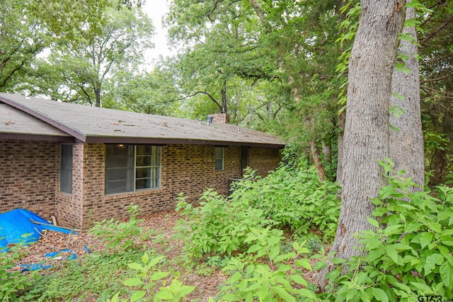 view of home's exterior featuring a chimney and brick siding