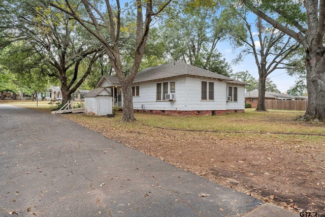 view of home's exterior with cooling unit, a storage shed, and a lawn