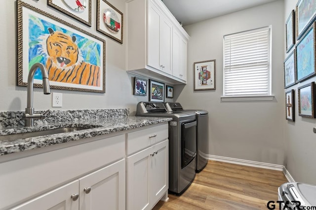 laundry area featuring light hardwood / wood-style floors, cabinets, independent washer and dryer, and sink