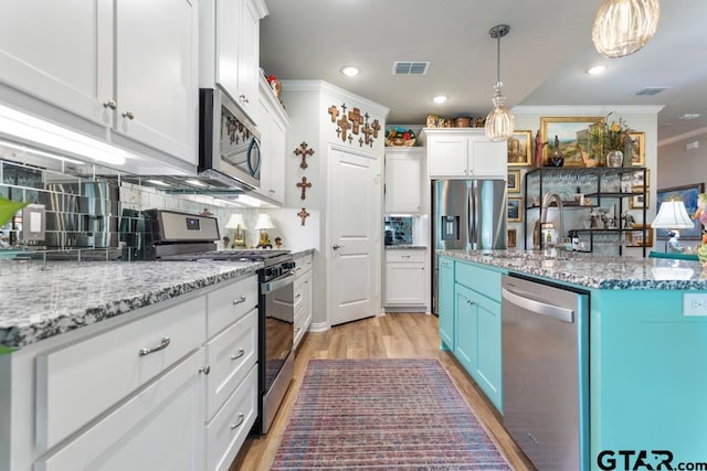 kitchen with stainless steel appliances, blue cabinets, pendant lighting, light hardwood / wood-style floors, and white cabinetry