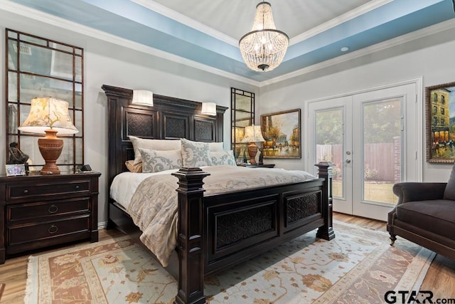 bedroom with access to outside, french doors, crown molding, light wood-type flooring, and a tray ceiling