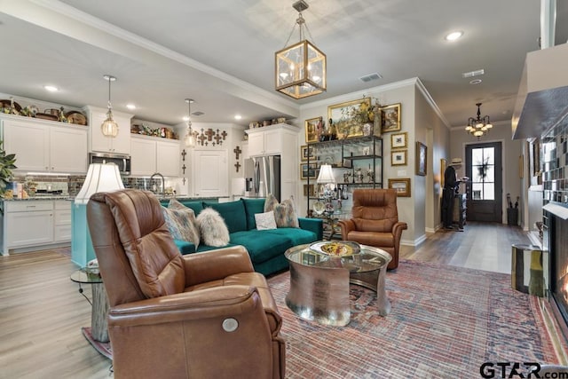 living room with light hardwood / wood-style floors, sink, and crown molding