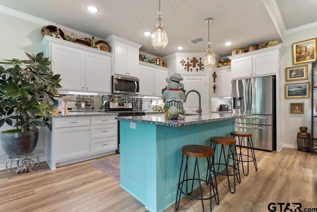 kitchen featuring light hardwood / wood-style floors, white cabinetry, an island with sink, and appliances with stainless steel finishes