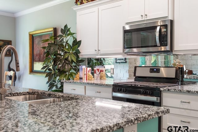 kitchen featuring decorative backsplash, appliances with stainless steel finishes, light stone counters, sink, and white cabinetry