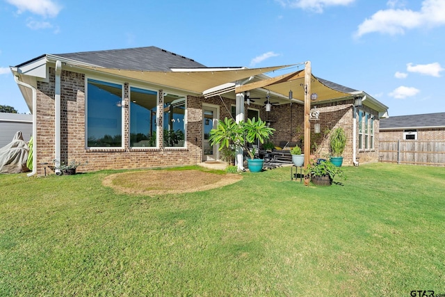 rear view of property with a lawn and ceiling fan