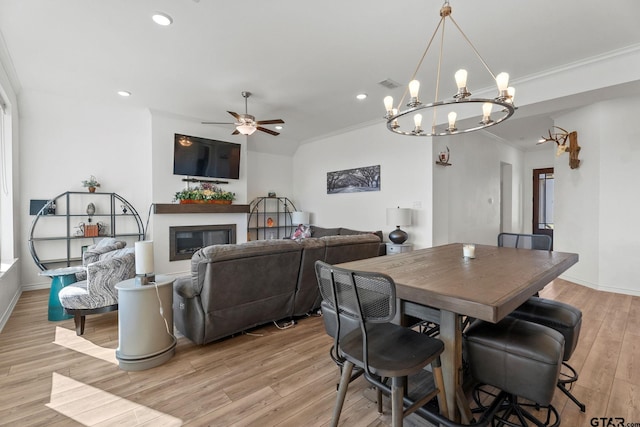 dining space featuring light wood-type flooring, crown molding, and ceiling fan with notable chandelier